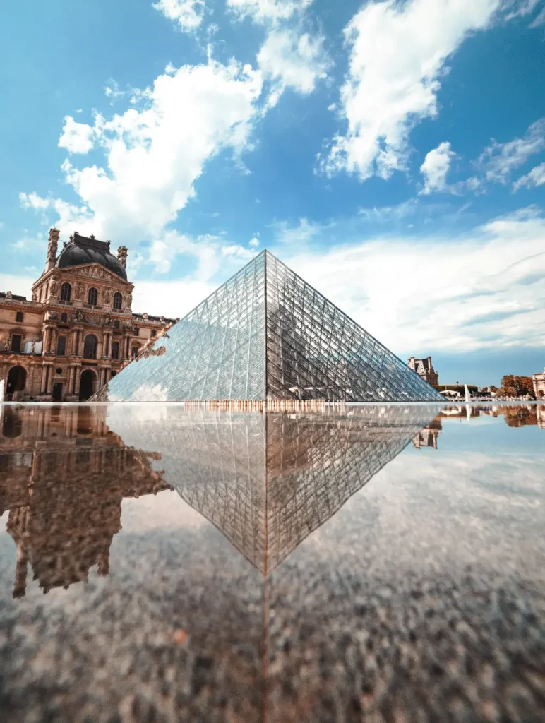 Louvre Pyramid reflected in fountain in Paris, France.
